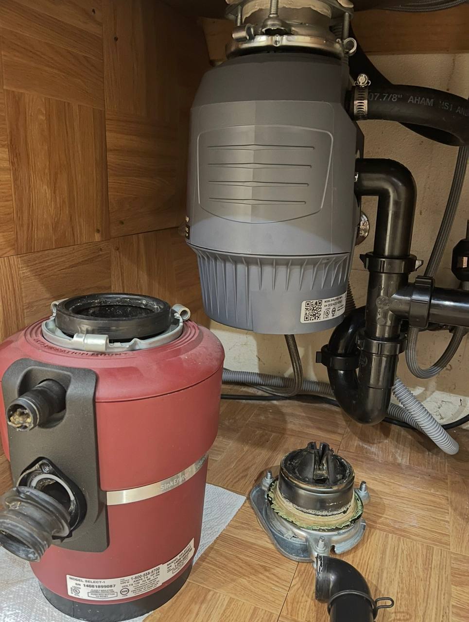Garbage disposal under a sink alongside the removed unit